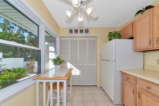 kitchen featuring light brown cabinets, ceiling fan, light tile patterned floors, a textured ceiling, and white fridge