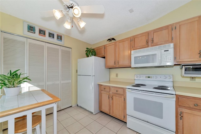 kitchen featuring white appliances, ceiling fan, a textured ceiling, light brown cabinetry, and light tile patterned flooring