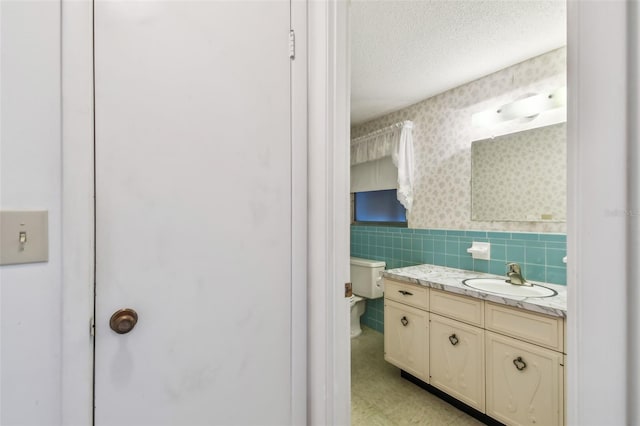 bathroom featuring a textured ceiling, vanity, and toilet