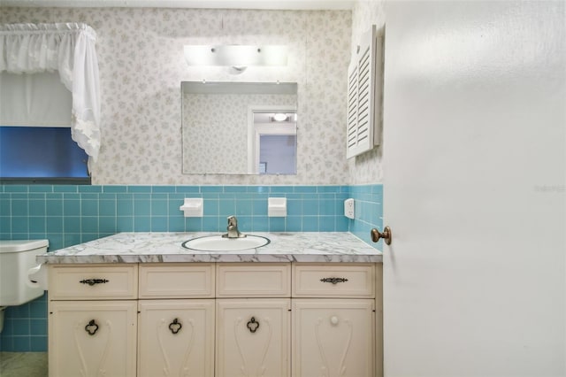 bathroom with vanity, toilet, and tile walls