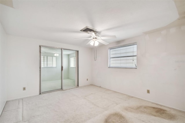 spare room featuring a wealth of natural light, ceiling fan, and light colored carpet