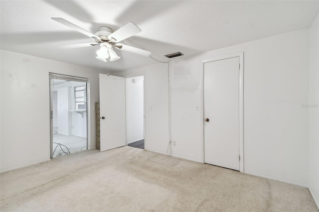 unfurnished bedroom featuring light carpet, a textured ceiling, and ceiling fan