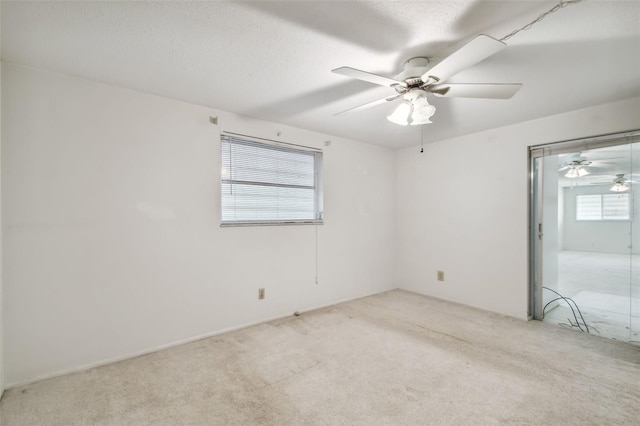 unfurnished room featuring a textured ceiling, light colored carpet, plenty of natural light, and ceiling fan