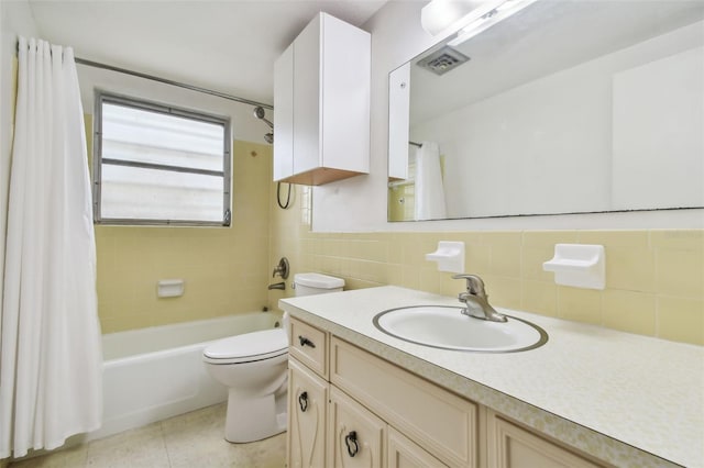 full bathroom with tile patterned flooring, tile walls, toilet, vanity, and shower / tub combo