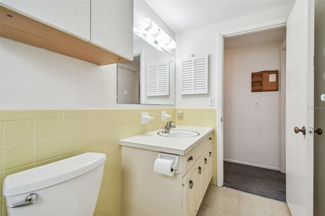 bathroom with vanity, tile patterned floors, toilet, tile walls, and a textured ceiling