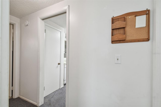 corridor with a textured ceiling and carpet floors