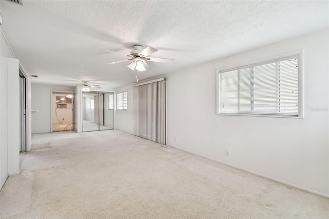 carpeted spare room featuring a textured ceiling and ceiling fan