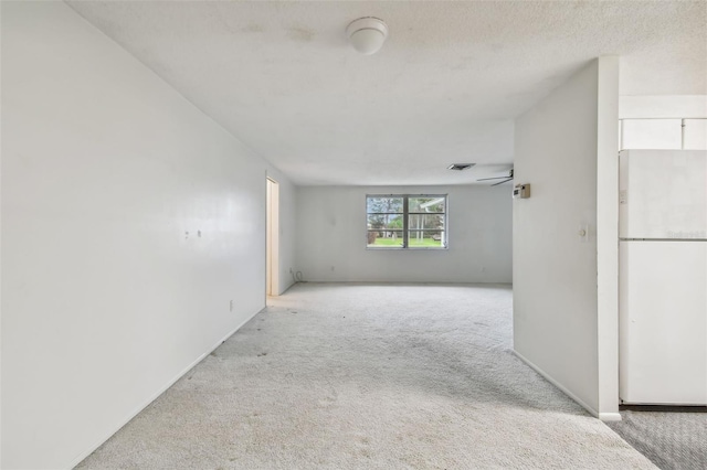 carpeted spare room featuring ceiling fan and a textured ceiling