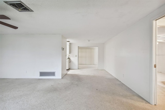 spare room featuring light carpet, a textured ceiling, and ceiling fan