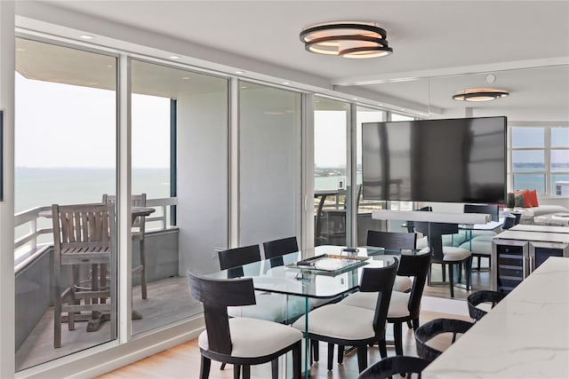 dining room with a water view, a wall of windows, and light hardwood / wood-style floors