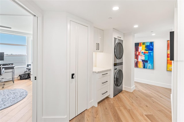 clothes washing area with stacked washer / drying machine and light hardwood / wood-style floors