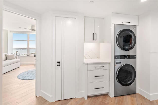 888 Blvd Of The Arts Unit 1705, Sarasota, FL 34236 - laundry room featuring stacked washing machine and dryer, light wood finished floors, baseboards, and a water view