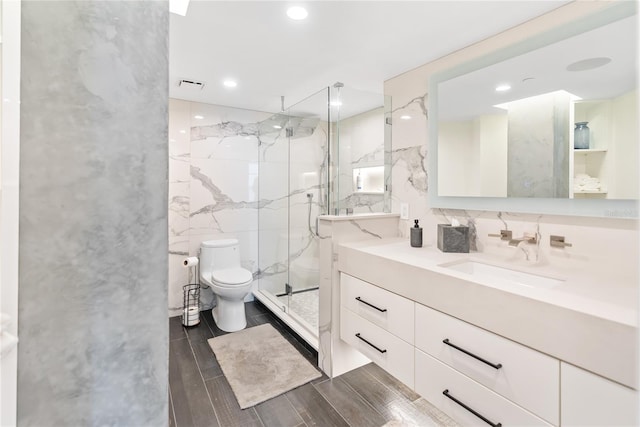 bathroom featuring walk in shower, hardwood / wood-style floors, toilet, vanity, and tile walls