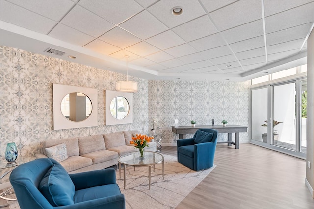 living room with a drop ceiling and light hardwood / wood-style flooring