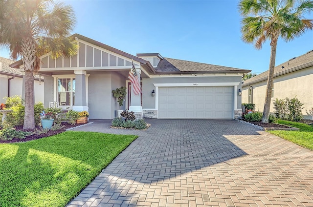 14924 Sora Way, Bradenton, FL 34212 - view of front of house with stucco siding, a garage, decorative driveway, a front lawn, and stone siding