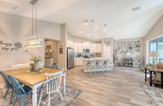 dining room featuring light wood-type flooring and high vaulted ceiling