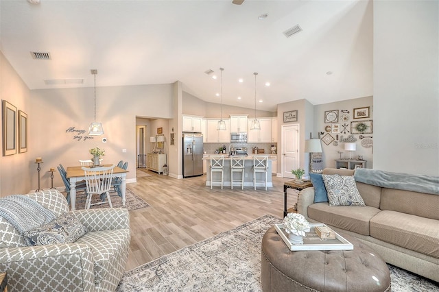 living room with light hardwood / wood-style floors and vaulted ceiling