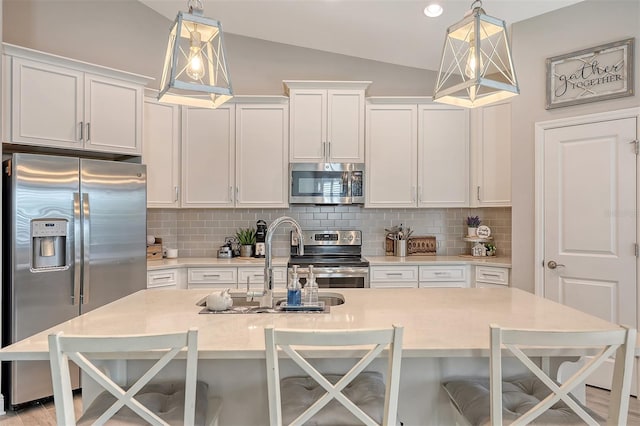 kitchen featuring lofted ceiling, white cabinets, hanging light fixtures, a breakfast bar area, and stainless steel appliances