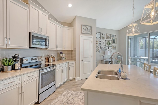 kitchen with white cabinets, appliances with stainless steel finishes, hanging light fixtures, and sink