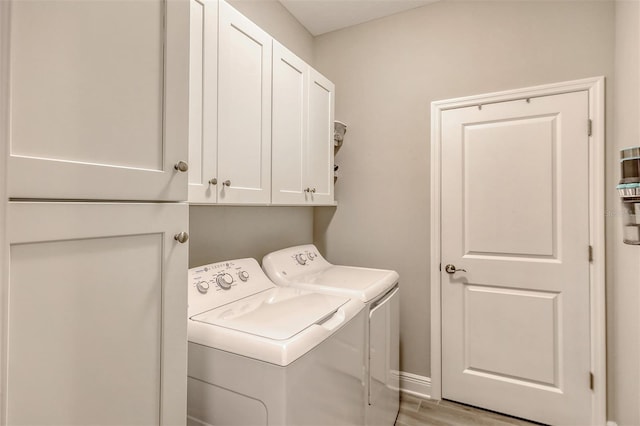 laundry room featuring cabinets, washing machine and dryer, and light hardwood / wood-style flooring