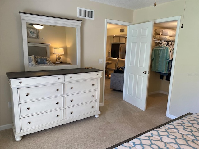 carpeted bedroom featuring a walk in closet, stainless steel refrigerator, and a closet