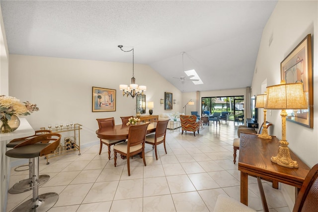 dining space featuring ceiling fan with notable chandelier, lofted ceiling with skylight, and light tile patterned floors