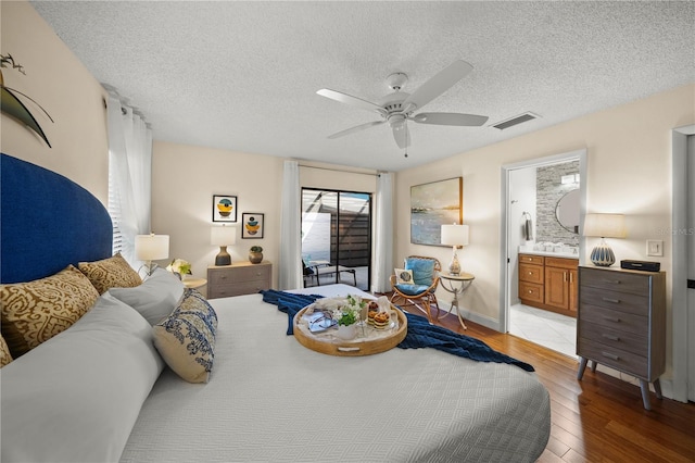 bedroom featuring ceiling fan, light wood-type flooring, a textured ceiling, and connected bathroom