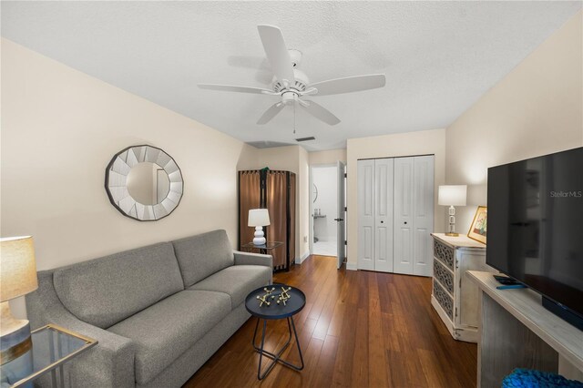 living room featuring ceiling fan, dark hardwood / wood-style flooring, and a textured ceiling