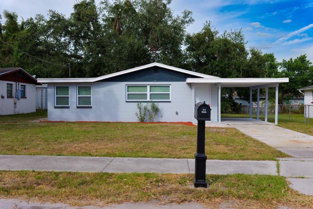 ranch-style house featuring a front lawn and a carport