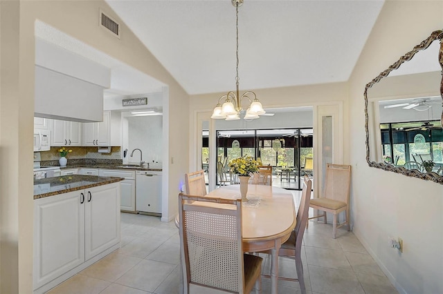 dining space with lofted ceiling, ceiling fan with notable chandelier, light tile patterned flooring, and visible vents