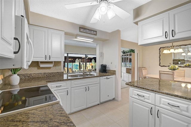 kitchen featuring white appliances, light tile patterned floors, white cabinets, a sink, and backsplash