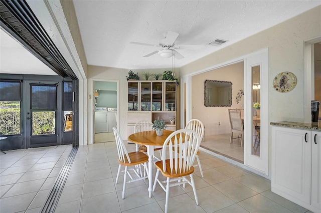 dining room featuring light tile patterned floors, visible vents, ceiling fan, a textured ceiling, and washer and dryer