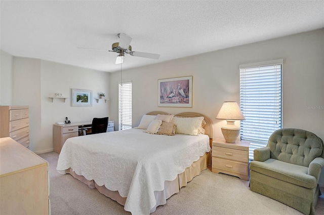 bedroom with a ceiling fan, light carpet, and a textured ceiling