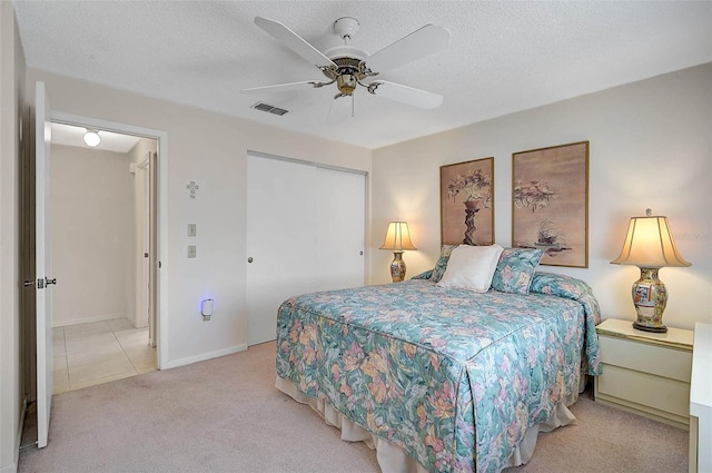 bedroom with light carpet, visible vents, ceiling fan, a textured ceiling, and a closet