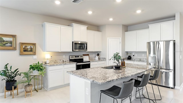 kitchen with white cabinets, stainless steel appliances, and a center island with sink