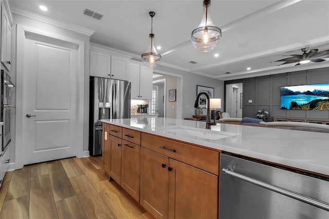 kitchen featuring appliances with stainless steel finishes, white cabinetry, sink, light hardwood / wood-style flooring, and crown molding