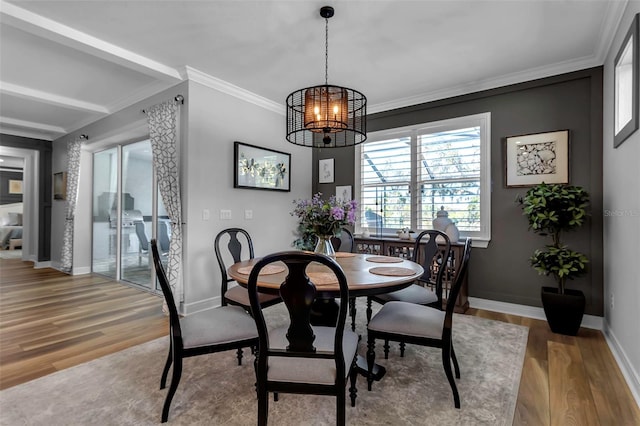 dining space with wood-type flooring, an inviting chandelier, and crown molding