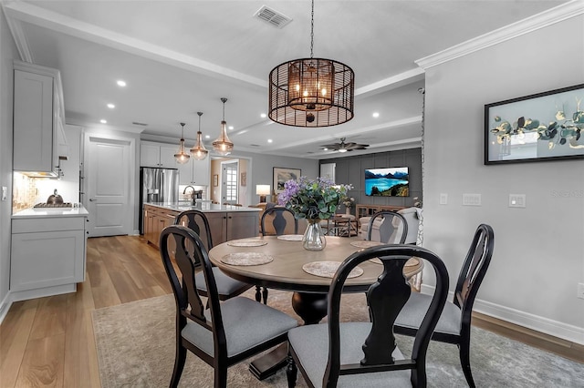 dining area with light hardwood / wood-style floors, sink, crown molding, and ceiling fan with notable chandelier