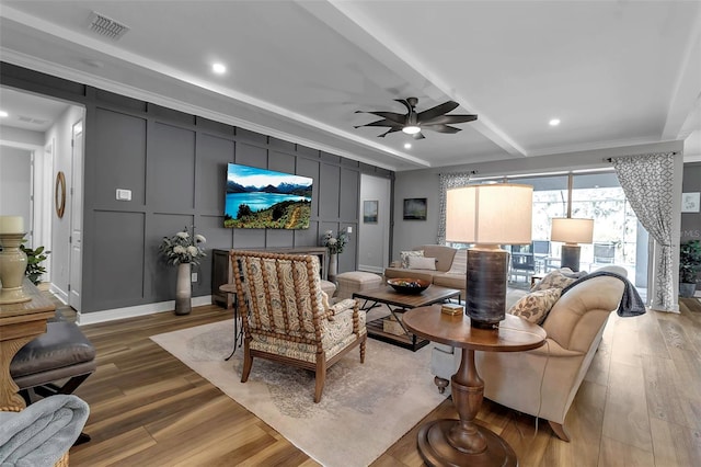 living room featuring crown molding, light hardwood / wood-style flooring, beamed ceiling, and ceiling fan