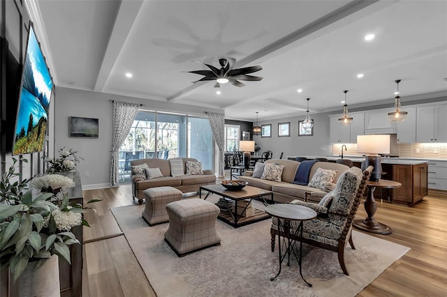 living room featuring sink, ceiling fan, beamed ceiling, and light hardwood / wood-style flooring