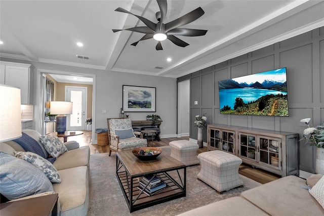 living room with ceiling fan, beamed ceiling, crown molding, and hardwood / wood-style floors