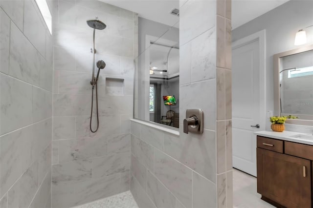 bathroom featuring a tile shower and vanity