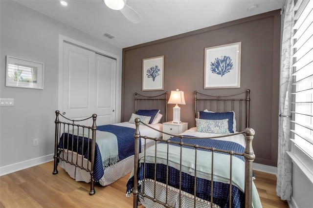 bedroom featuring a closet, ceiling fan, multiple windows, and wood-type flooring