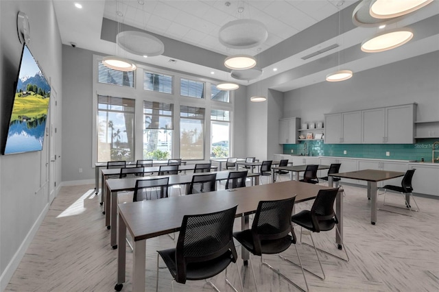 dining room with a high ceiling, sink, and a raised ceiling