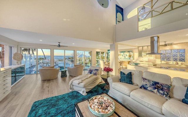 living room featuring a high ceiling, light hardwood / wood-style flooring, a wealth of natural light, and ceiling fan