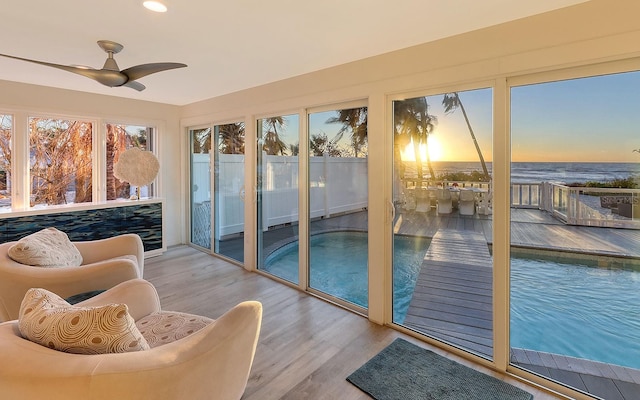 sunroom featuring ceiling fan and a water view