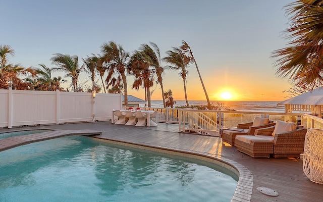 pool at dusk featuring a deck with water view