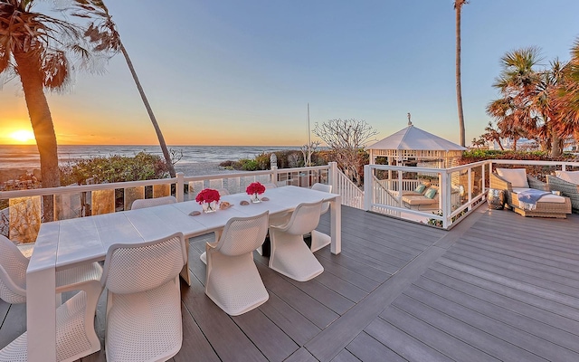 deck at dusk with a gazebo and a water view