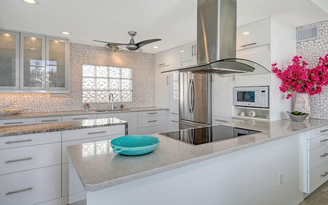 kitchen with white cabinetry, sink, backsplash, stainless steel fridge, and island range hood