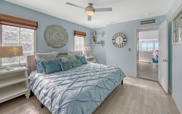 bedroom featuring ceiling fan, light hardwood / wood-style flooring, and multiple windows